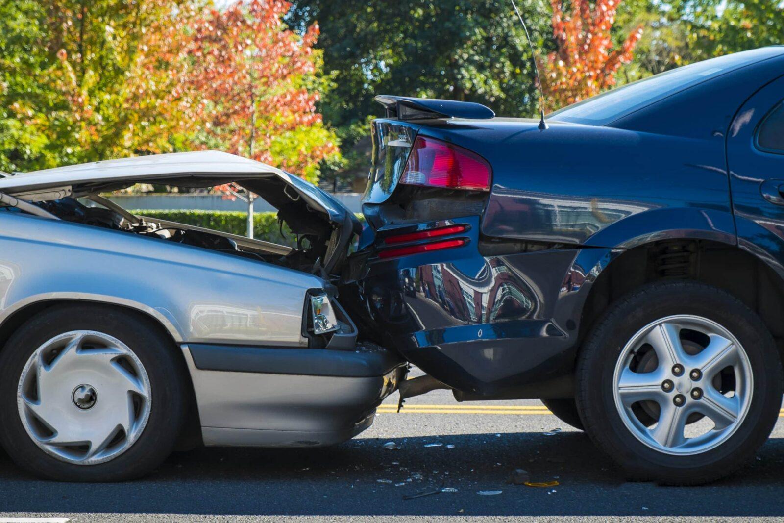A rear-end car accident involving 2 vehicles on a city street, showing significant damage to both cars.