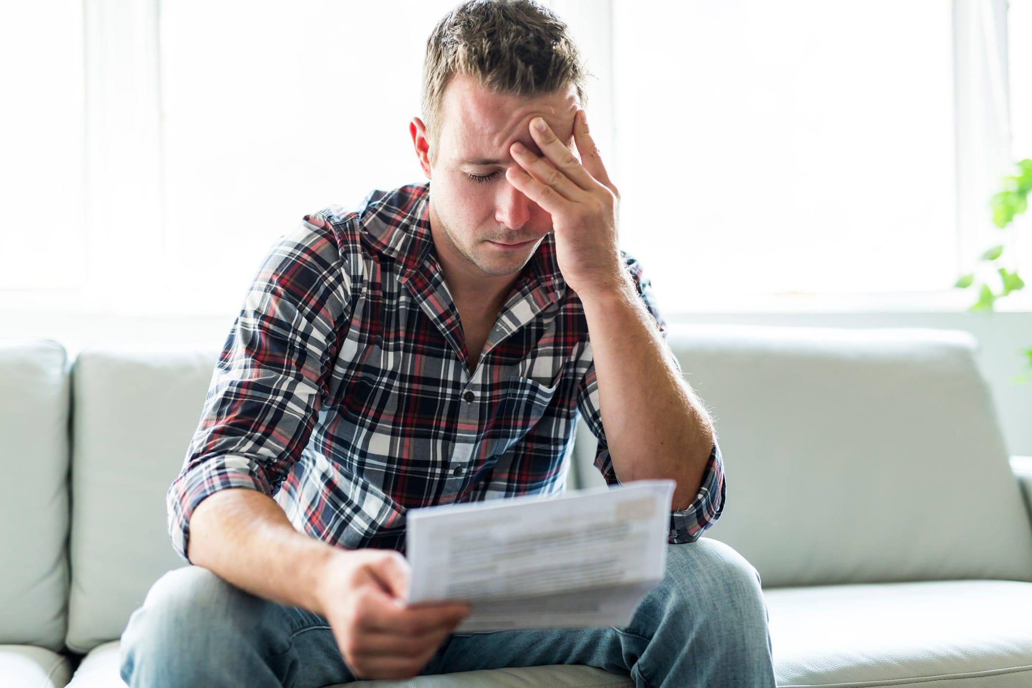 A man feeling stressed reading through his bills after a car accident in Midland, TX.